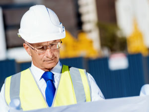 Man looking at blue prints in white hardhat | SAE Inc.